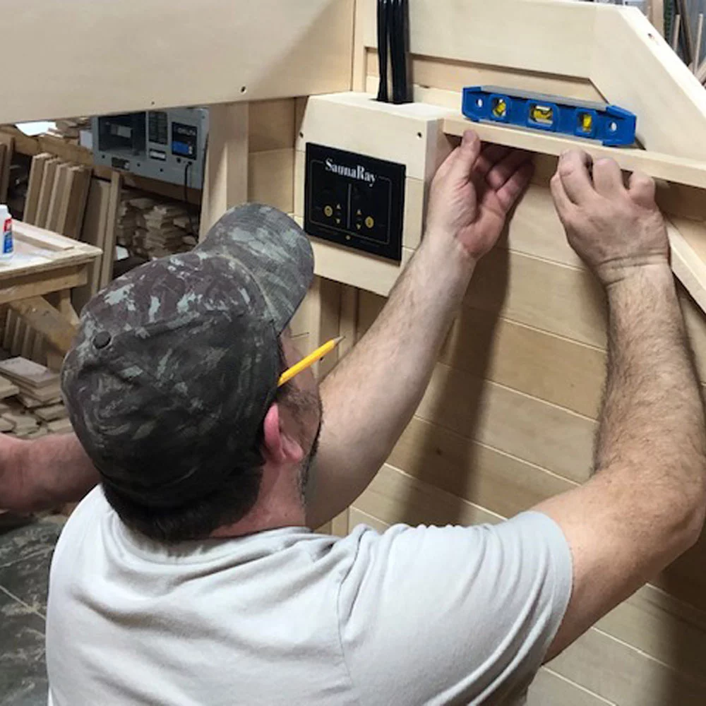 A man working with a level reviewing a custom infrared sauna, made in Canadian Basswood by SaunaRay